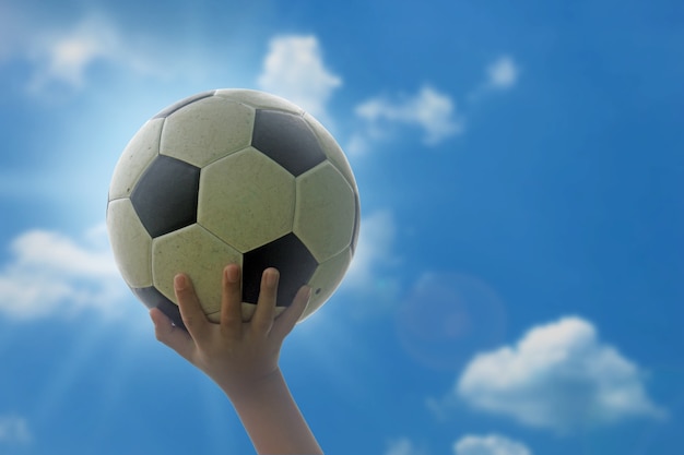 The boy holds the soccer ball over his head. 