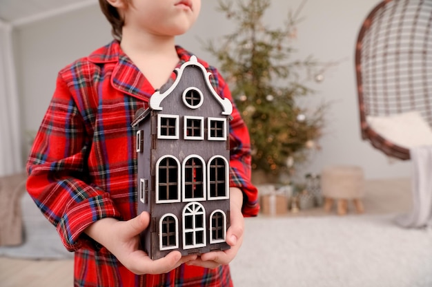 소년은 크리스마스 트리 앞에서 목조 주택을 보유하고 있다