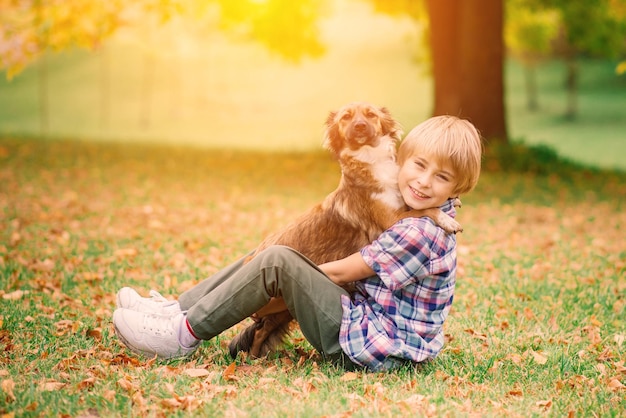 Boy hugging a dog and playing with in the fall city park