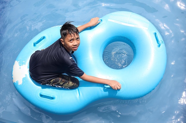 Boy on the inflatable ring in swimming pool Summer water play