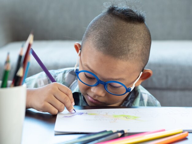 Boy intend drawing a picture fun, enjoy drawing or write in book at home.  