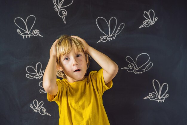 The boy is bitten by mosquitoes on a dark background On the blackboard with chalk painted mosquitoes