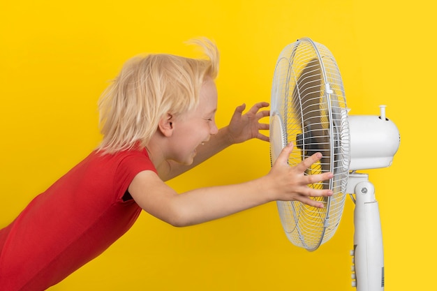 Boy is enjoying the cold air of the fan