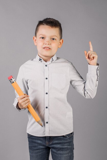 Boy is holding a big pencil concept of school education