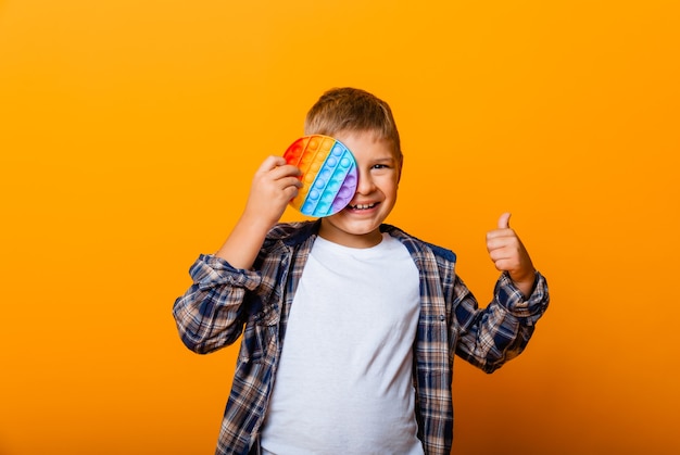 The boy is holding sensory flapping toys in his hands. Push pop-it game. Happy boy with pop it