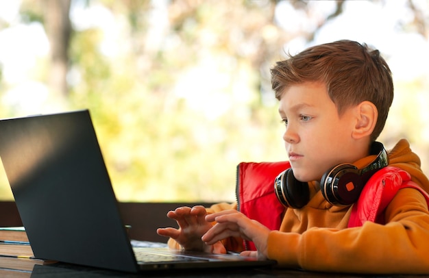 the boy is looking intently at the monitor outdoors