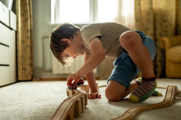 男の子は家でおもちゃの列車で遊んでいます子供は木製の構造物から鉄道を作っています