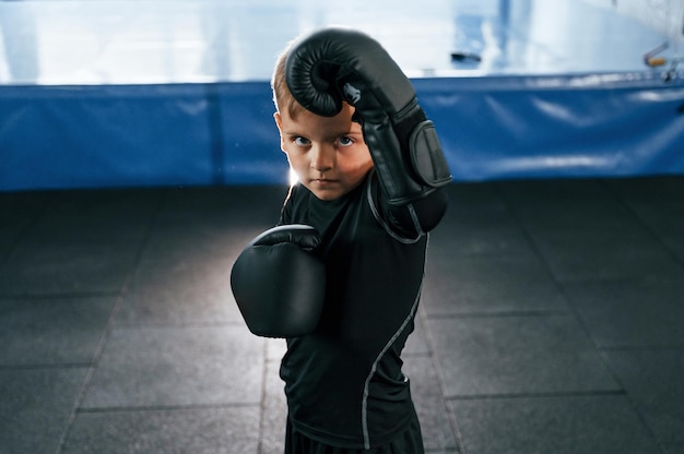 Photo boy is practicing boxing in the gym with glowes on hands