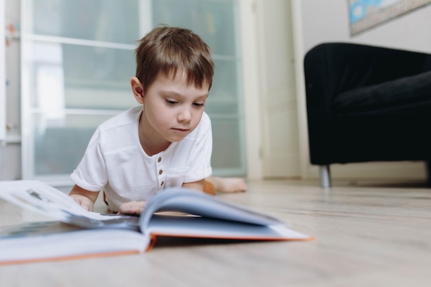 A boy is reading a book on the floor at home image with selective focus