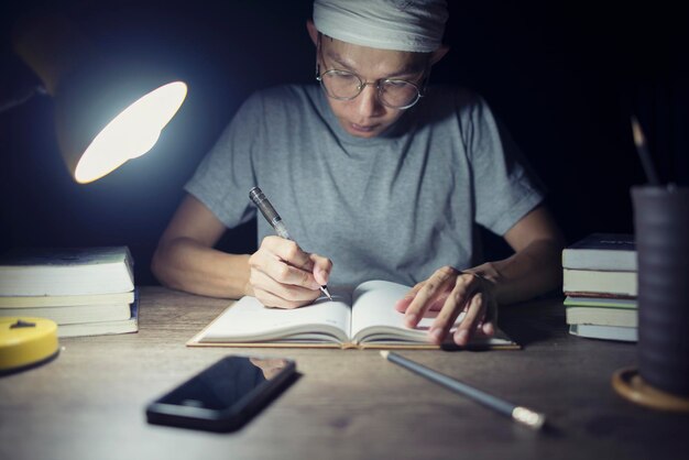 Мальчик читает книги по подготовке к экзамену, пишет заметки с намерением. Крупный план, написанный от руки.