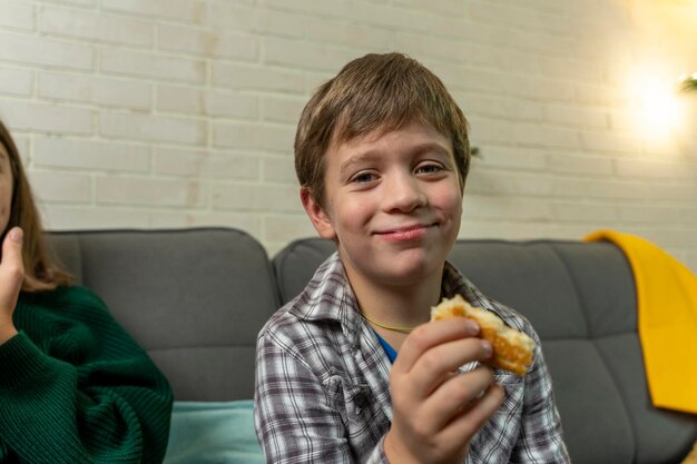 Boy is sitting at home on the couch eating pizza and watching TV