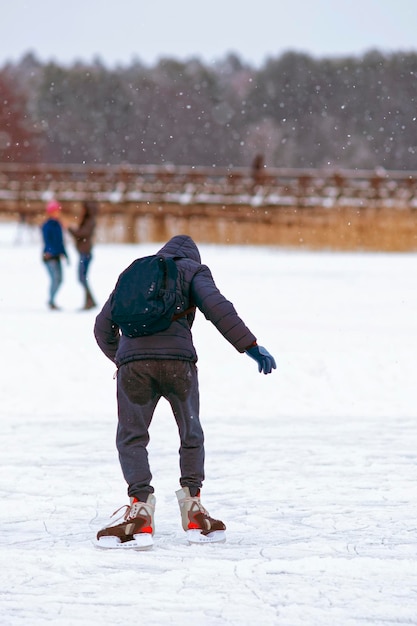 Boy is skating in the rink in winter. skating involves any\
sports or recreational activity which consists of traveling on\
surfaces or on ice using skates.