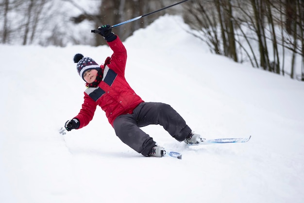 The boy is skiing in the winter forest A child falls while learning to ski