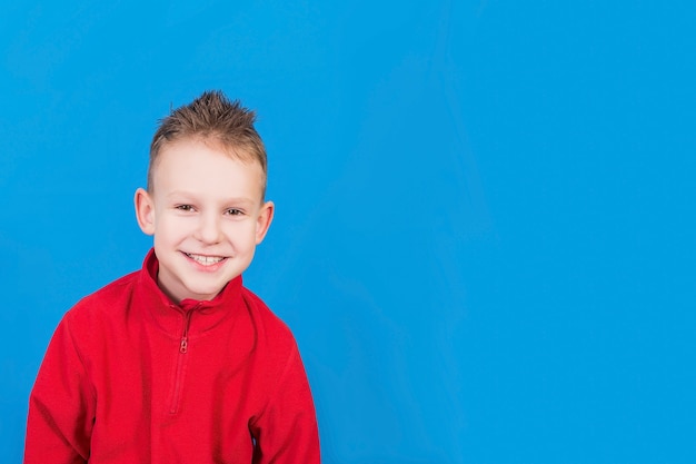 The boy is smiling on a blue surface