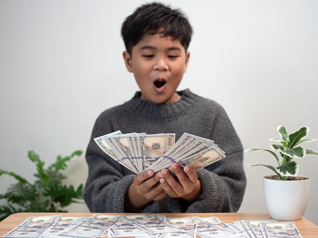 Мальчик с радостью держит деньги Концепция сбережения денег Инвестиционные финансы