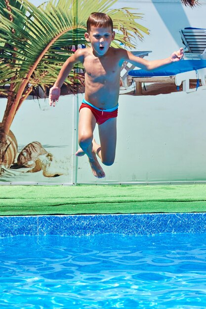 Boy jumping into resort pool