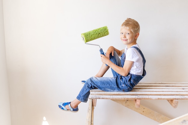 Boy in jumpsuit holding painting roller