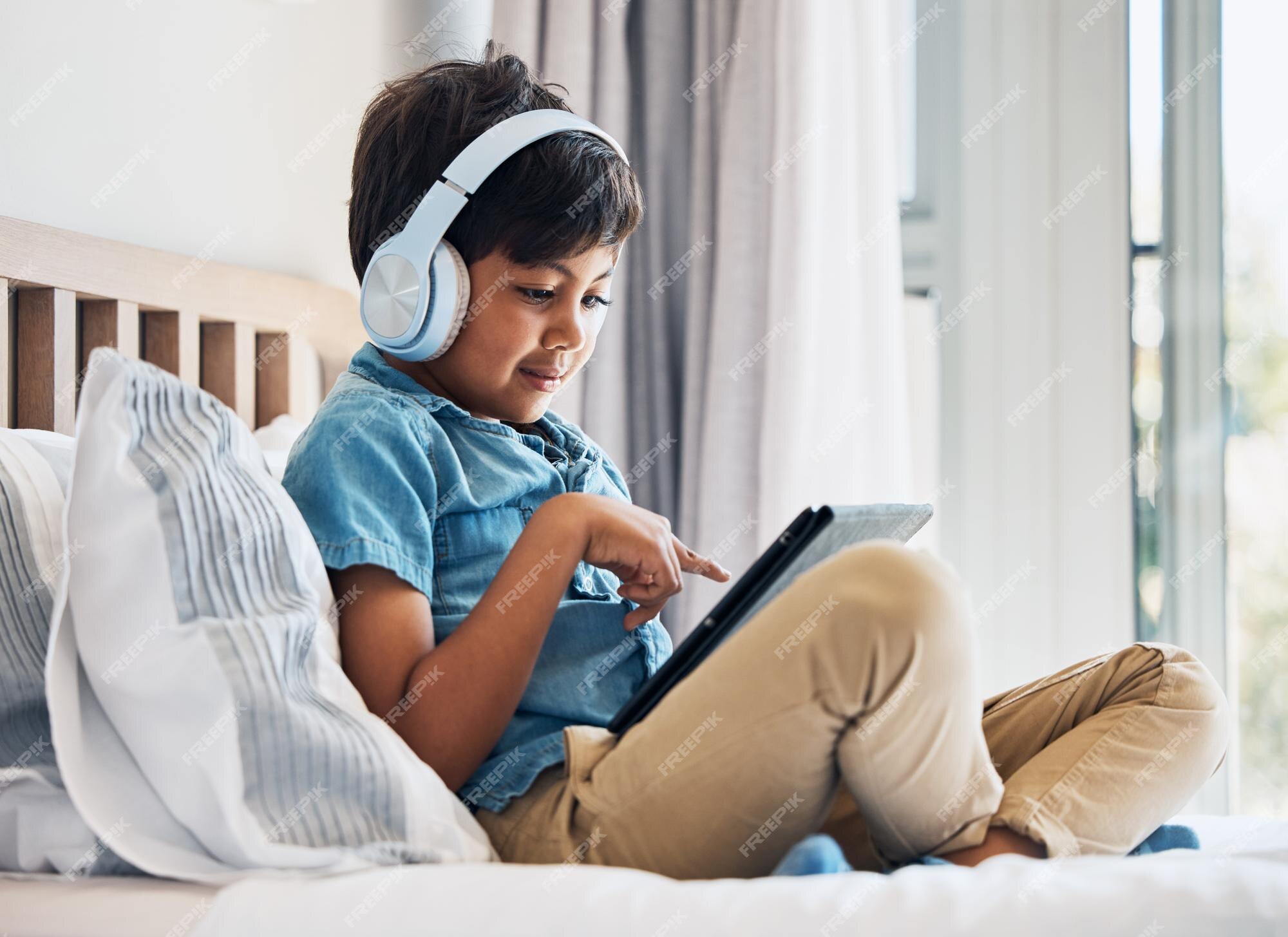 Premium Photo  Boy kid and headphones with tablet on bed for online games  watching movies or play educational app happy child digital technology or  listening to multimedia music or streaming cartoon