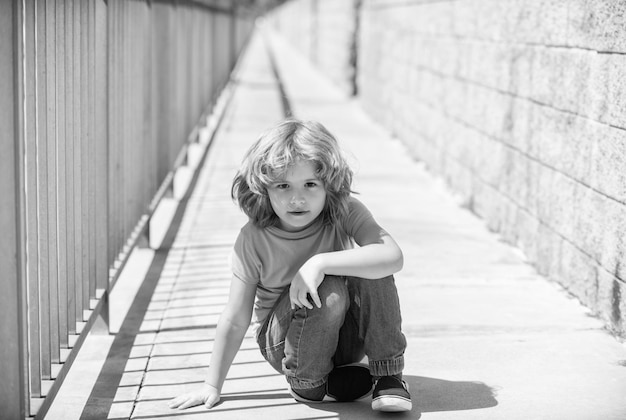 Boy kid take rest sitting down on promenade on summer outdoors resting