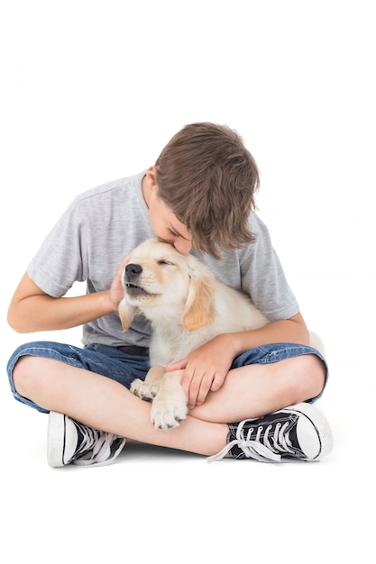 Boy kissing puppy over white background