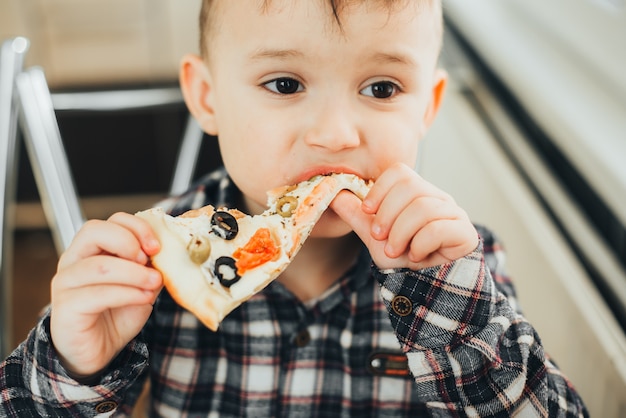 The boy in the kitchen at home eating pizza with salmon