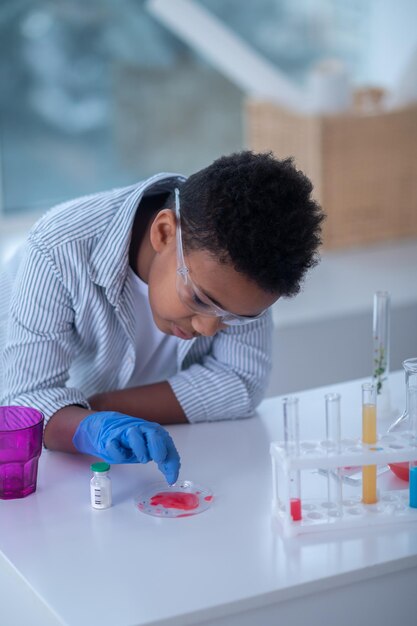 Photo a boy in a lab coat working with test tubes and looking involved