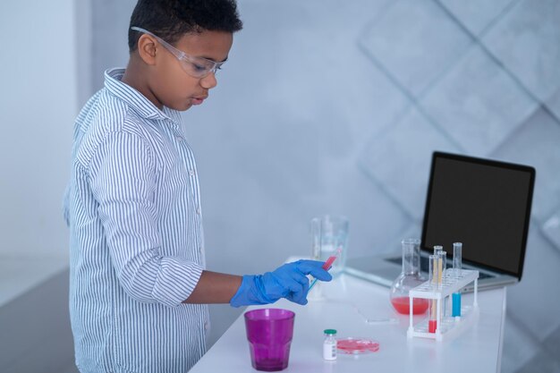 Photo a boy in a lab coat working with test tubes and looking involved