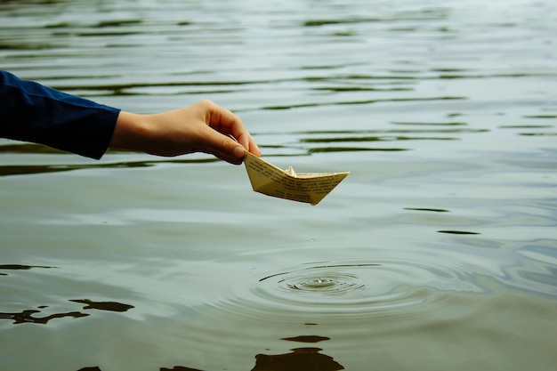 The boy launches a boat on a water closeup