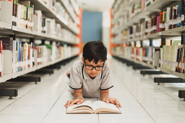 Мальчик лежит на полу и читает книгу в библиотеке Концепция образования