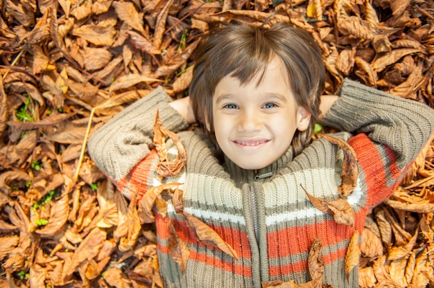 写真 乾燥した葉の上に横たわる少年