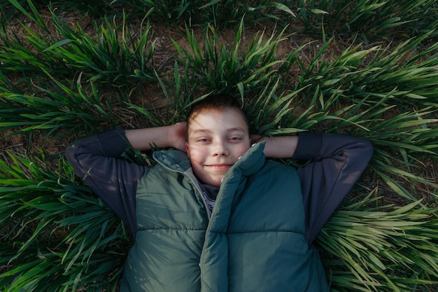 A boy laying in the grass with his hands behind his head