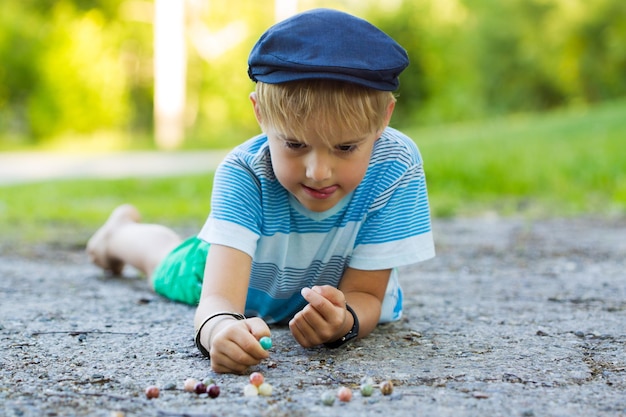 Foto un ragazzo sdraiato a terra con un cappello blu e uno sfondo di erba verde.