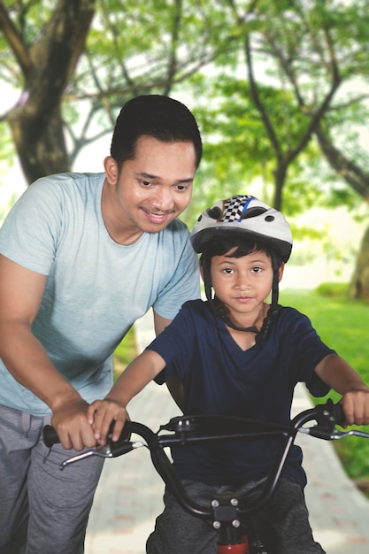 公園で父親と自転車に乗ることを学ぶ少年