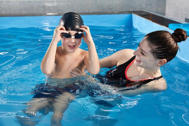Мальчик учится плавать и нырять в бассейне с учителем
