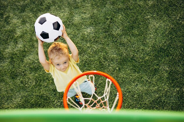 Photo boy learning to throw a ball into the basket