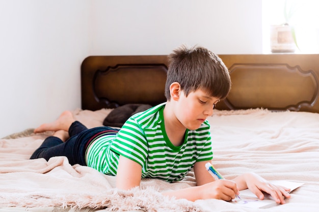 Boy lies on bed and reads a book