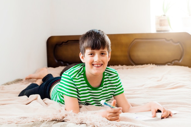 Boy lies on bed and reads a book