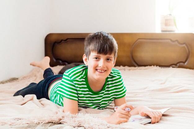 Boy lies on bed and reads a book