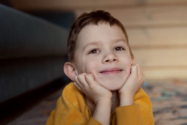 The boy lies on the floor with a smile