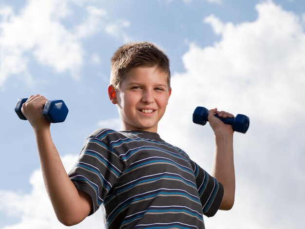 Boy lifting dumbbells outdoors