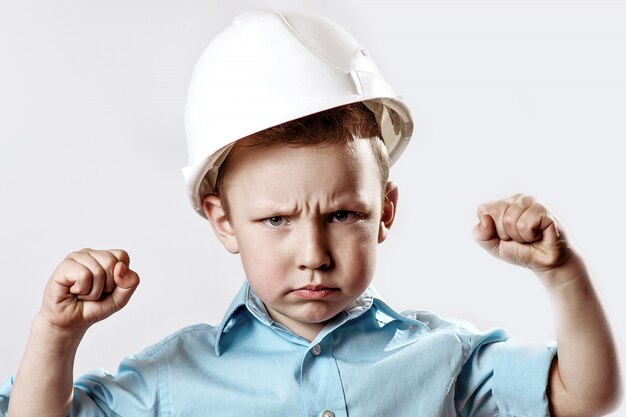 Boy in a light shirt and helmet Builder shows how he is strong and confident