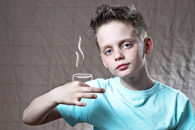 Boy in a light t-shirt holding a painted Cup of tea or coffee