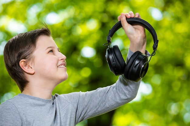 Boy  listening a music by huge headphones in outside forest
