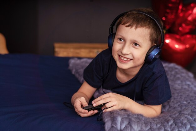 Boy listening to music in headphones Lying in bed