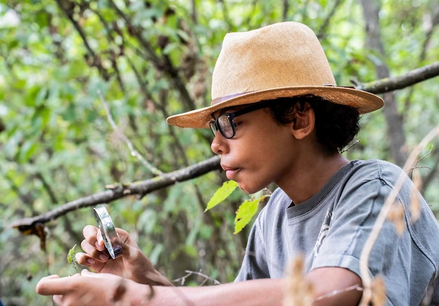 写真 拡大鏡で葉を見ている少年 自然のマイクロ世界を探している 自然と環境の概念を愛するティーンエイジャー