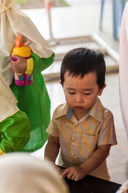 テーブルのそばに立って遠くを見ている少年