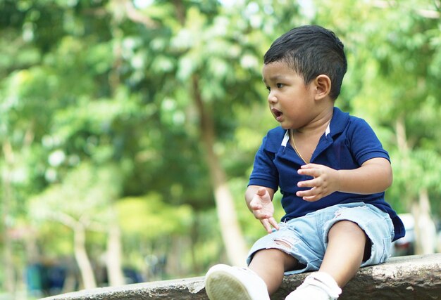 Boy looking away while sitting outdoors