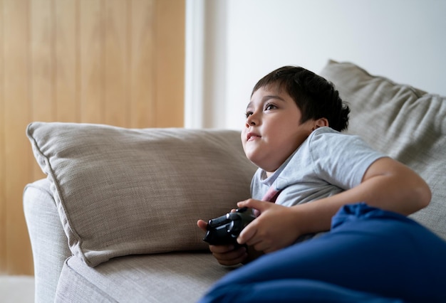 Boy looking away while sitting on sofa at home