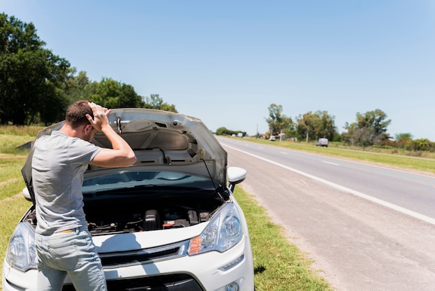 Photo boy looking at broken down car