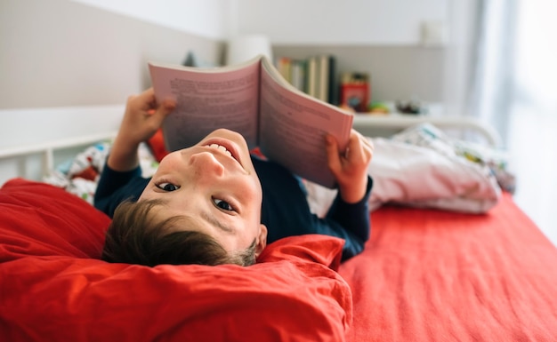 本を読みながらカメラを見ている少年